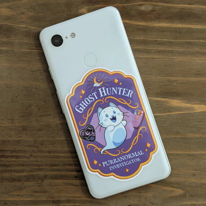Phone with a spooky cute ghost-hunter themed sticker badge