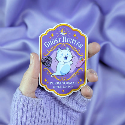 Spooky cute ghost hunter badge sticker held by a hand