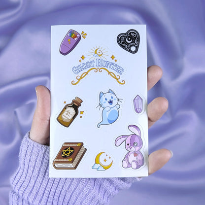 Sheet of 'Ghost Hunter' themed stickers held by a hand against a purple background