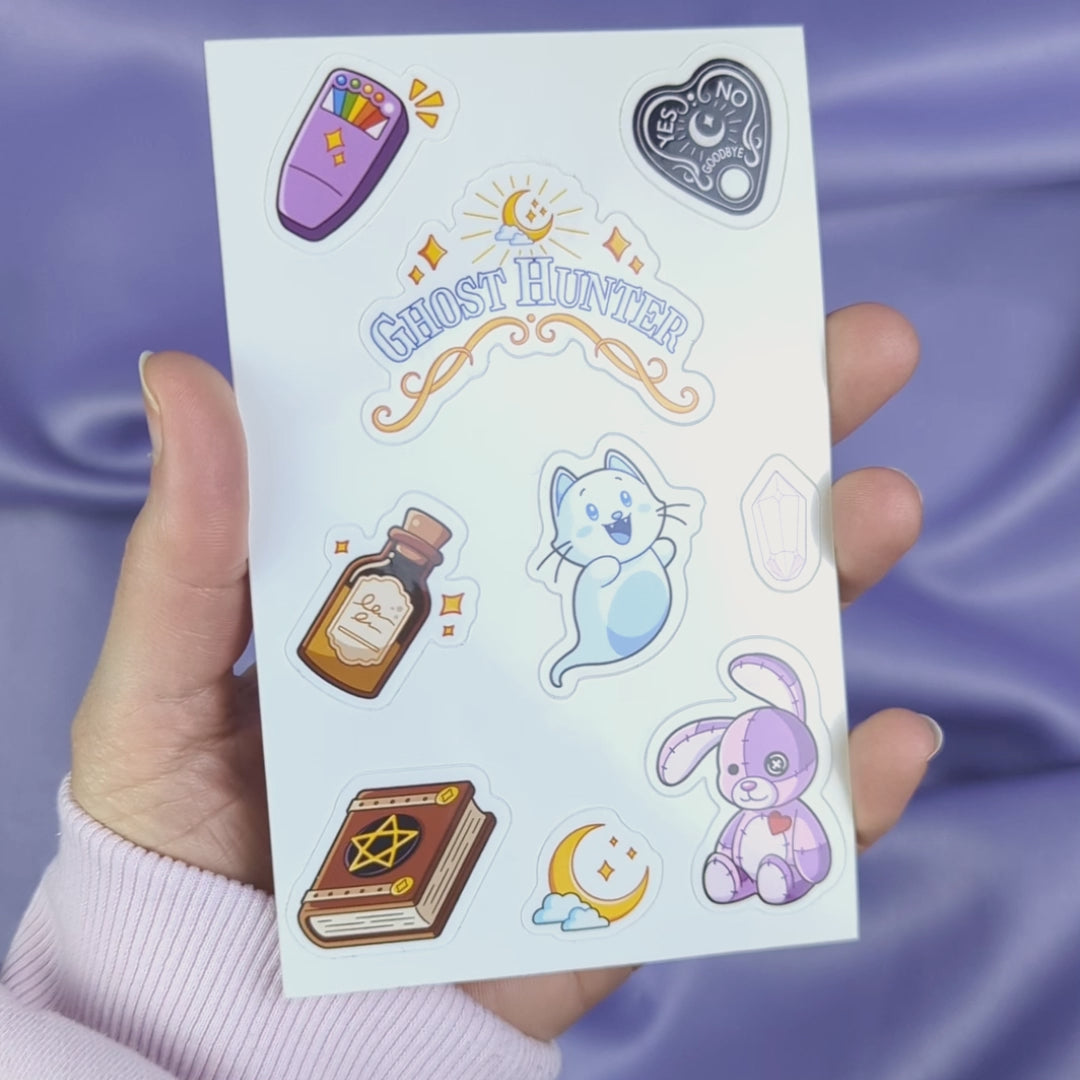 Video of a sheet of 'Ghost Hunter' themed stickers held by a hand against a purple background