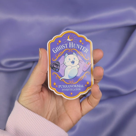 Video of a spooky cute ghost hunter badge sticker held by a hand
