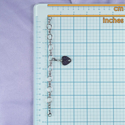 Chain with a heart-shaped charm on a grid ruler with measurements in cm and inches.