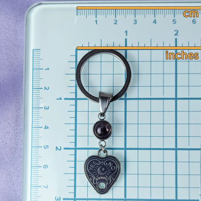 Keychain with heart-shaped spiritboard pendant on a ruler for scale